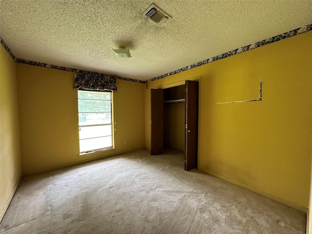 unfurnished bedroom with carpet, a textured ceiling, and a closet