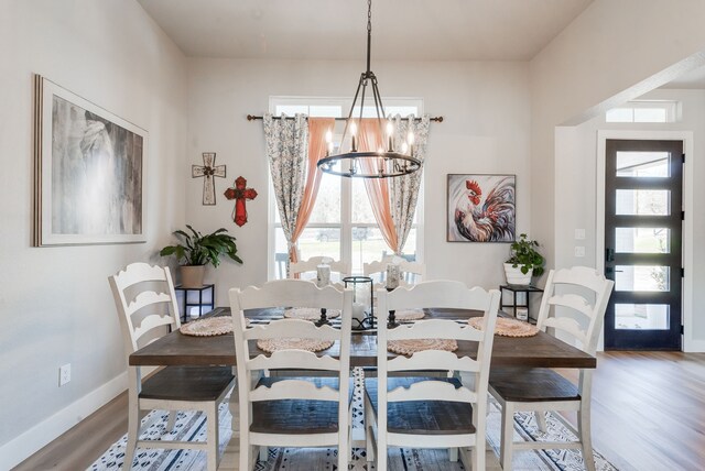 dining space with hardwood / wood-style floors and an inviting chandelier