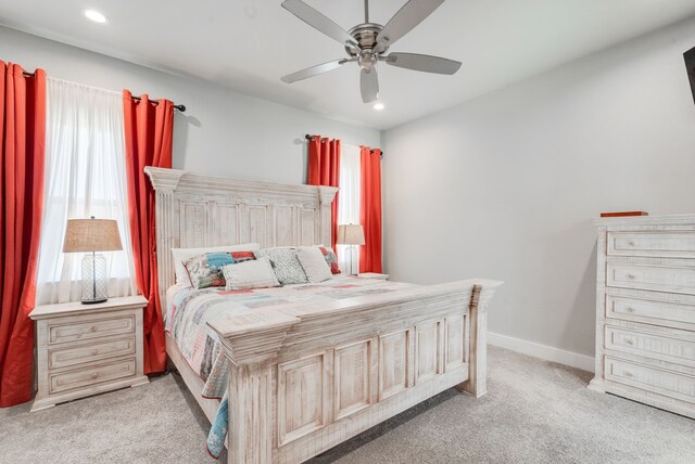 bedroom with multiple windows, ceiling fan, and light carpet