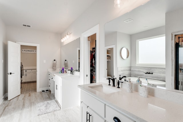 bathroom featuring hardwood / wood-style floors, vanity, and a bath