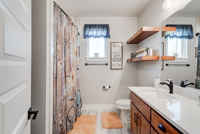 bathroom featuring vanity, a healthy amount of sunlight, and toilet