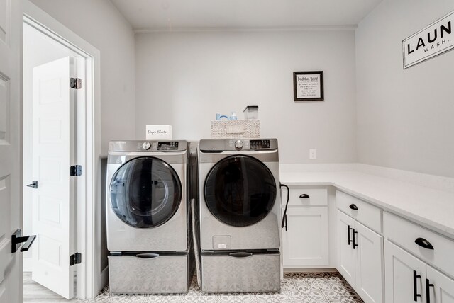 laundry room featuring washer and dryer, cabinets, and light tile patterned floors