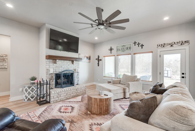 living room with ceiling fan, light hardwood / wood-style flooring, and a brick fireplace