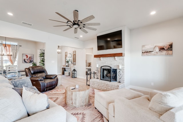 living room featuring ceiling fan with notable chandelier and light hardwood / wood-style flooring