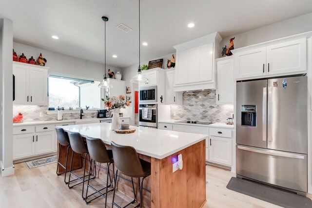 kitchen featuring white cabinetry, a center island, pendant lighting, and appliances with stainless steel finishes