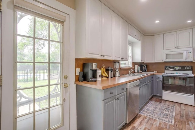 kitchen featuring white appliances, sink, gray cabinets, light wood-type flooring, and white cabinetry