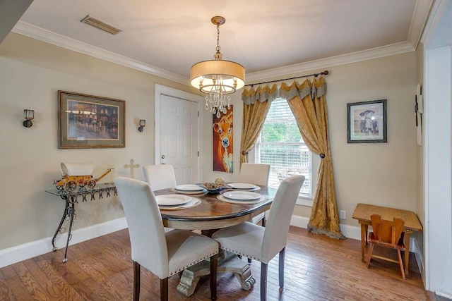 dining area with hardwood / wood-style floors, ornamental molding, and a notable chandelier