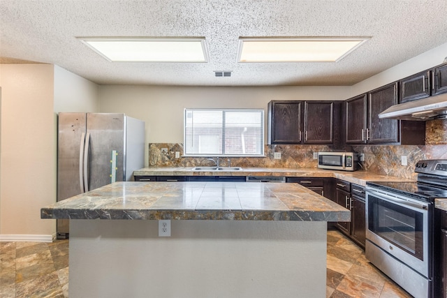 kitchen featuring appliances with stainless steel finishes, a center island, tasteful backsplash, and sink