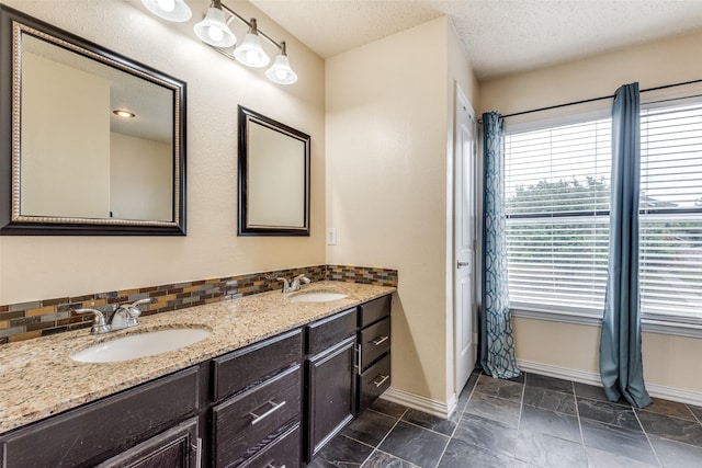 bathroom with decorative backsplash, vanity, and a textured ceiling