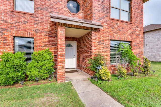 view of exterior entry featuring a yard