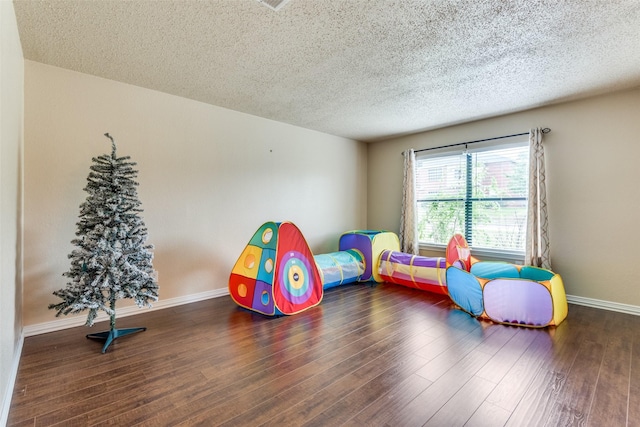 recreation room with dark hardwood / wood-style floors and a textured ceiling