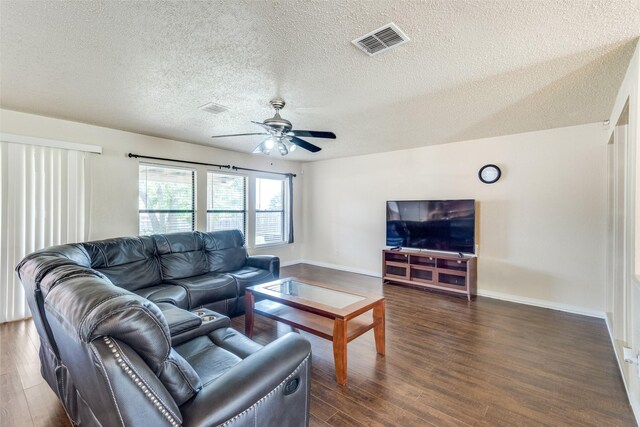 living room featuring ceiling fan, dark wood-type flooring, and a textured ceiling