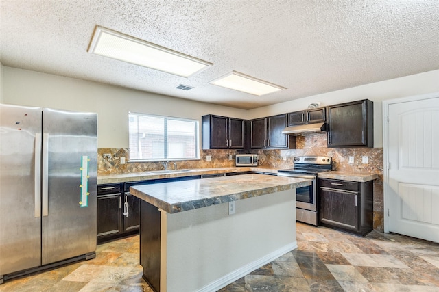 kitchen featuring dark brown cabinetry, sink, stainless steel appliances, tasteful backsplash, and a kitchen island