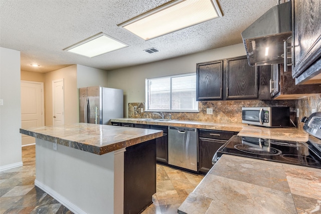 kitchen featuring sink, stainless steel appliances, backsplash, extractor fan, and a kitchen island