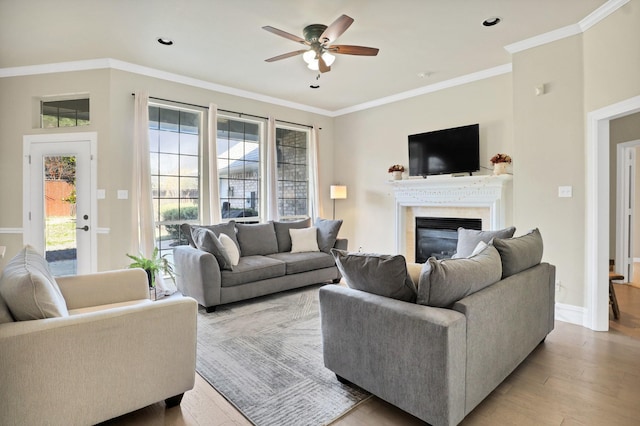 living room featuring light hardwood / wood-style flooring, ceiling fan, and ornamental molding