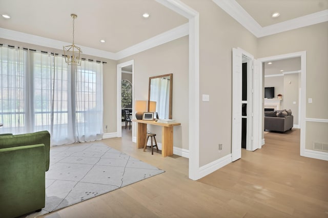 interior space with an inviting chandelier, ornamental molding, and light hardwood / wood-style floors