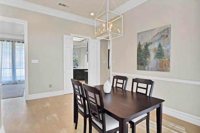 dining area with an inviting chandelier, light hardwood / wood-style flooring, and crown molding