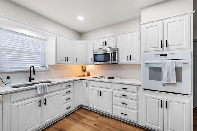 kitchen featuring white cabinetry, wood-type flooring, white appliances, and sink