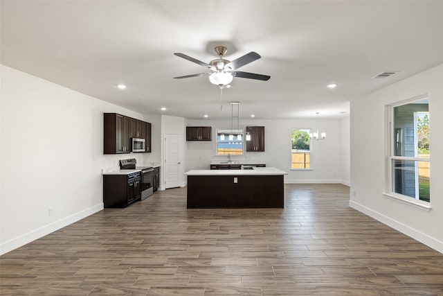 kitchen featuring sink, stainless steel appliances, decorative light fixtures, a kitchen island, and ceiling fan with notable chandelier