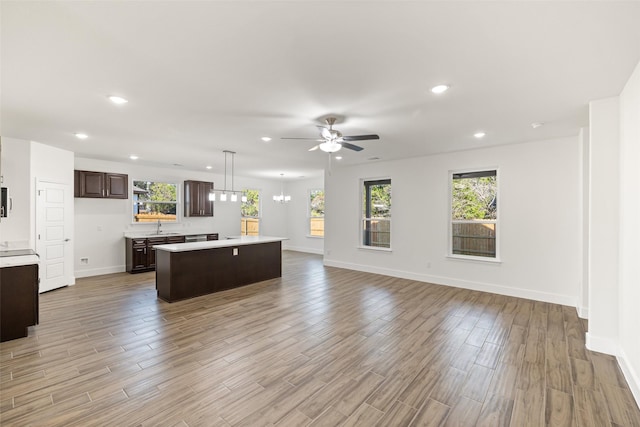 kitchen with a center island, ceiling fan with notable chandelier, sink, hanging light fixtures, and dark brown cabinetry