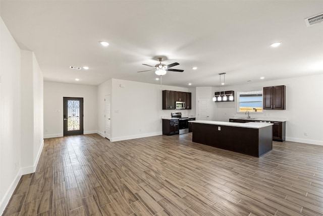 kitchen featuring appliances with stainless steel finishes, dark brown cabinets, ceiling fan, a kitchen island, and hanging light fixtures