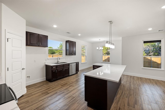 kitchen with stainless steel dishwasher, dark brown cabinets, sink, decorative light fixtures, and a center island