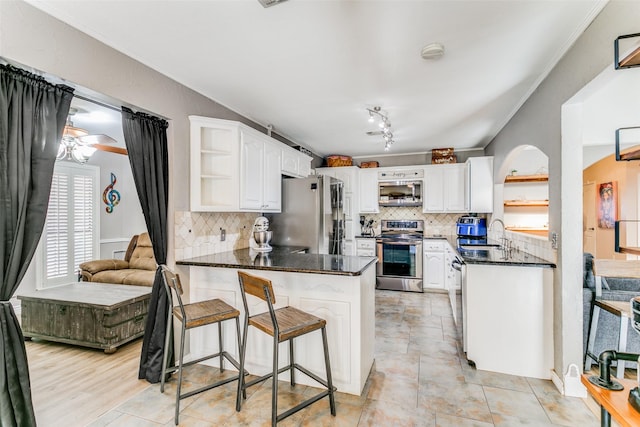 kitchen with stainless steel appliances, white cabinetry, ornamental molding, and kitchen peninsula