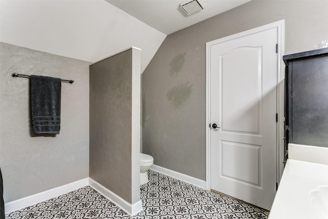 bathroom featuring vanity, toilet, and vaulted ceiling