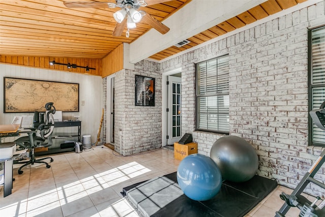 exercise room with wooden ceiling, light tile patterned floors, wooden walls, ceiling fan, and brick wall