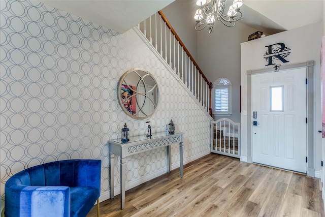 entrance foyer with hardwood / wood-style flooring, a towering ceiling, and an inviting chandelier