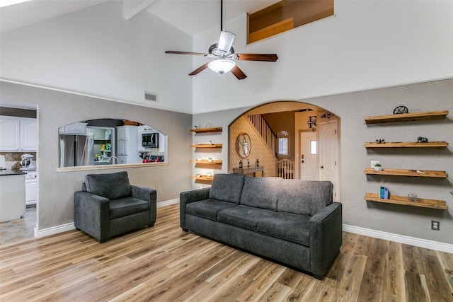 living room featuring beamed ceiling, ceiling fan, high vaulted ceiling, and light wood-type flooring