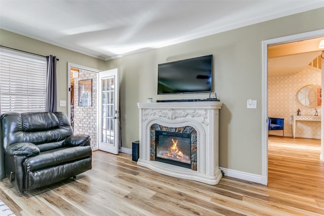 living room with ornamental molding, a high end fireplace, and light hardwood / wood-style flooring