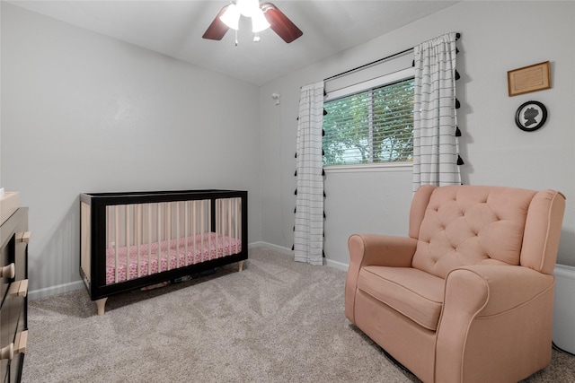 carpeted bedroom featuring a crib and ceiling fan