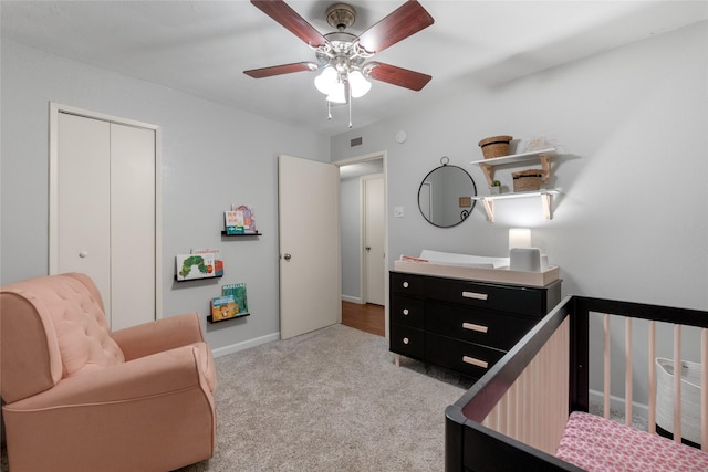 carpeted bedroom featuring ceiling fan, a crib, and a closet