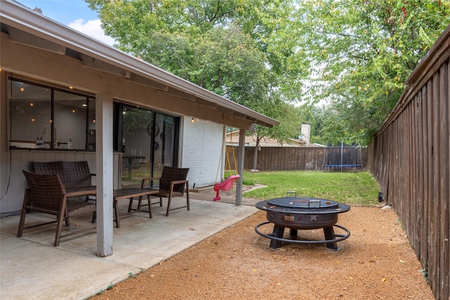 view of yard with a trampoline, an outdoor fire pit, and a patio area