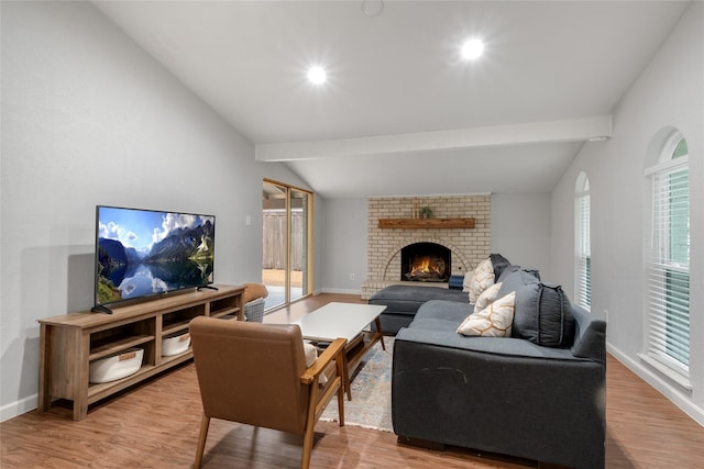 living room with a wealth of natural light, lofted ceiling with beams, a fireplace, and light hardwood / wood-style floors