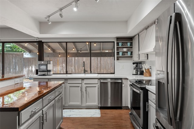 kitchen with appliances with stainless steel finishes, tasteful backsplash, sink, gray cabinetry, and dark hardwood / wood-style flooring