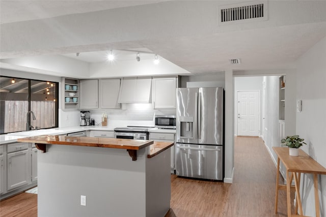 kitchen featuring wood counters, a center island, custom range hood, and stainless steel appliances