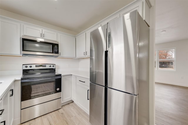 kitchen with stainless steel appliances, white cabinets, and light hardwood / wood-style flooring