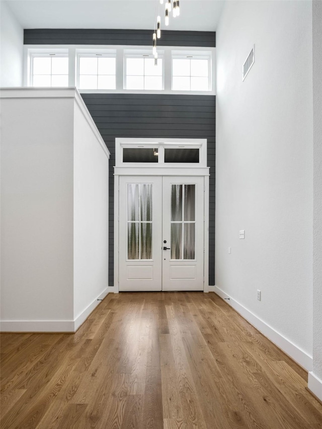 foyer entrance with french doors, a high ceiling, and hardwood / wood-style flooring