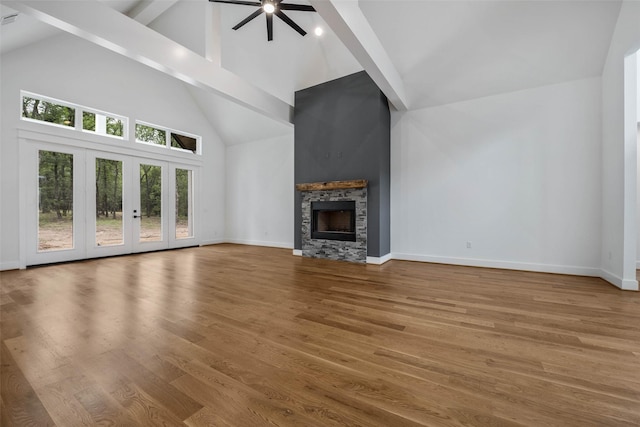 unfurnished living room with a fireplace, hardwood / wood-style floors, high vaulted ceiling, and beam ceiling