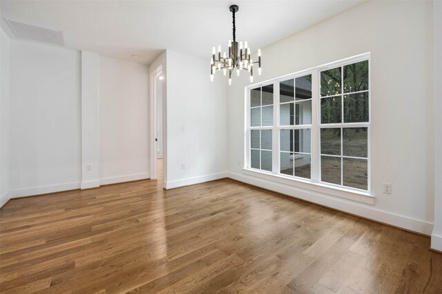 unfurnished dining area with a chandelier and hardwood / wood-style flooring