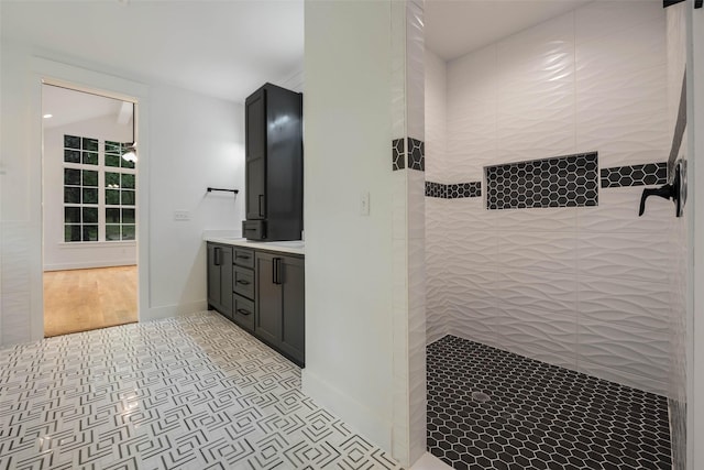 bathroom with a tile shower and vanity