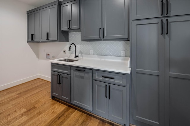 kitchen featuring backsplash, gray cabinetry, sink, and light hardwood / wood-style floors