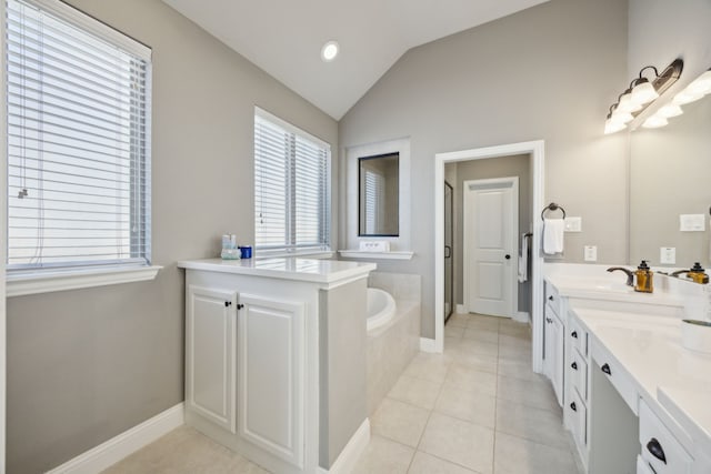 bathroom featuring tile patterned flooring, vaulted ceiling, tiled tub, and vanity