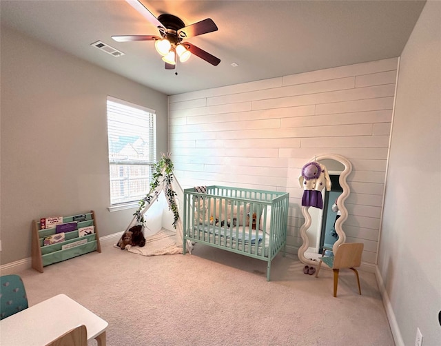 bedroom featuring carpet floors, a crib, and ceiling fan