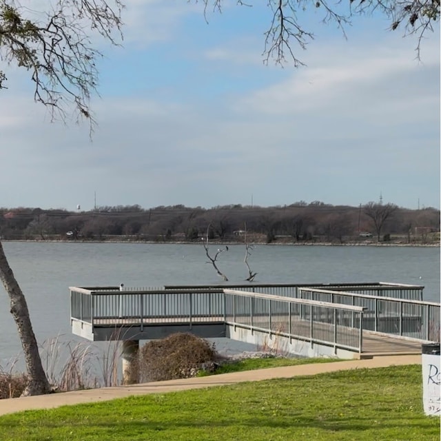 view of dock with a lawn and a water view