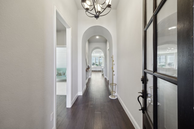 hall with dark hardwood / wood-style flooring and a notable chandelier