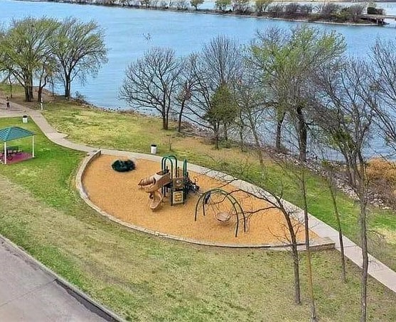 view of community featuring a lawn, a playground, and a water view