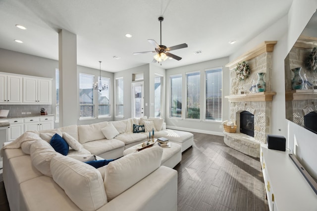 living room with dark wood-type flooring, a fireplace, and ceiling fan with notable chandelier